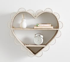 a heart shaped shelf with two shelves holding books and an alarm clock