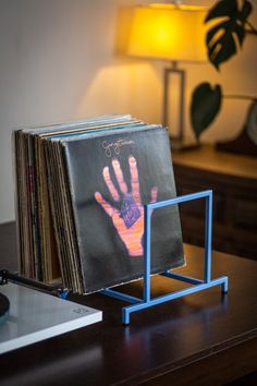 a stack of records sitting on top of a wooden table next to a light and lamp