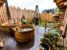 a wooden deck with two hot tubs on it's sides and plants in the middle