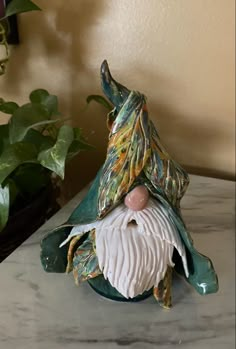 a ceramic figurine is sitting on a table next to a potted plant