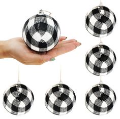 black and white ornament hanging from a string in front of a woman's hand