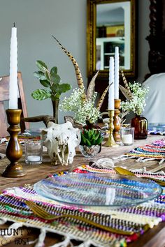 a wooden table topped with lots of plates and vases filled with flowers on top of it