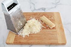 the grated cheese is next to a grater on a cutting board