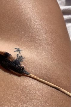 a woman's stomach with a tattoo on the side and a feather sticking out of it