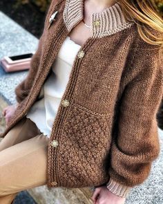 a woman sitting on a bench wearing a brown cardigan