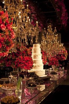 a wedding cake is surrounded by flowers and chandeliers