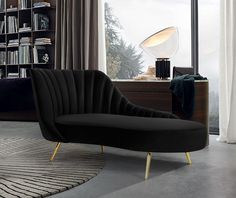 a black chair sitting in front of a window next to a book shelf filled with books