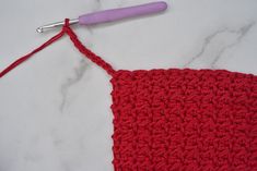 the crochet stitch is being worked on with a pink handled crochet hook