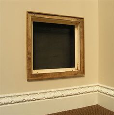 an empty room with a chalkboard hanging on the wall and carpeted flooring