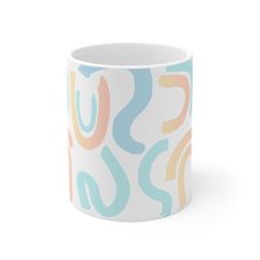 a white coffee mug with multicolored shapes on the outside and inside, sitting in front of a white background