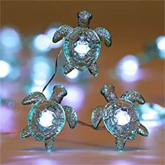 three turtle shaped diamond studs sitting on top of a wooden table with lights in the background