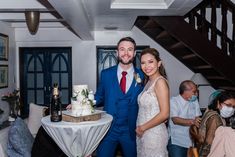 a man and woman standing next to each other in front of a table with a cake on it