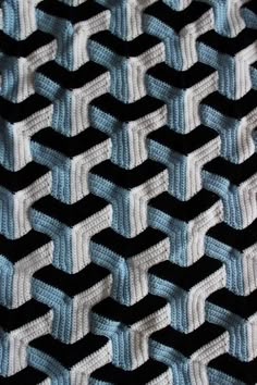 a black and white knitted blanket with blue strips on the edges is shown in close up