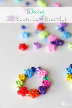 the words daisy girl scout law bracelet are made out of plastic beads and colorful bows