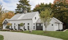 a white house with black shutters on the front and side doors is surrounded by trees