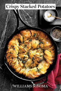 a skillet filled with food on top of a table next to other dishes and utensils