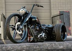 a black motorcycle is parked in front of a building with its wheels still on the ground