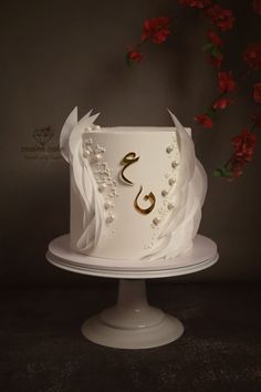 a white wedding cake with gold lettering and flowers