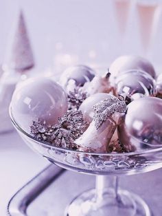 a glass bowl filled with white and silver ornaments