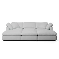 a white couch with four pillows on it's back end and one arm facing the camera