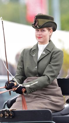 a woman riding on the back of a horse drawn carriage with a bow in her hand