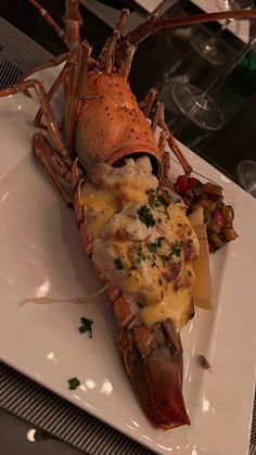 a lobster on a plate with cheese and vegetables