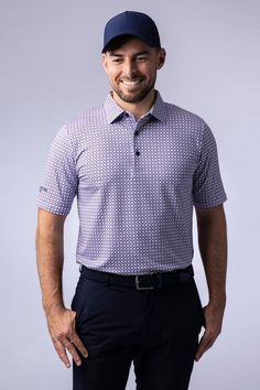 a man wearing a baseball cap and blue shirt smiles at the camera with his hands in his pockets