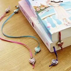 an open book sitting on top of a wooden table next to beads and bracelets