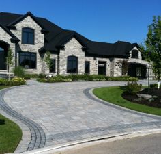 a large house that has a driveway in front of it and landscaping around the entrance