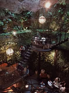 people are sitting at tables in the middle of a spiral staircase with plants growing on it