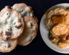 some cookies and peanut butter are on a white plate next to a bowl of oatmeal