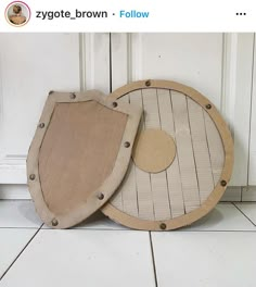 two wooden shields sitting on the floor next to each other