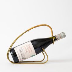 a bottle of wine in a metal holder on a white background with a gold handle