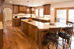 a large kitchen with wooden cabinets and marble counter tops, along with hardwood flooring