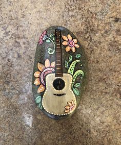 a guitar shaped rock sitting on top of a counter next to a tile floor with flowers painted on it