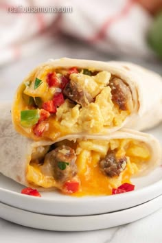 two breakfast burritos sitting on top of a white plate