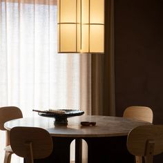 a dining room table with four chairs and a light fixture hanging from the ceiling over it