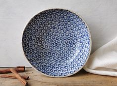 a blue and white bowl sitting on top of a wooden table next to cinnamon sticks