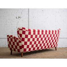 a red and white checkered couch sitting on top of a rug next to a brick wall