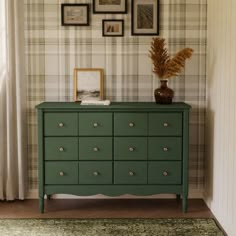 a green dresser in a room with pictures on the wall