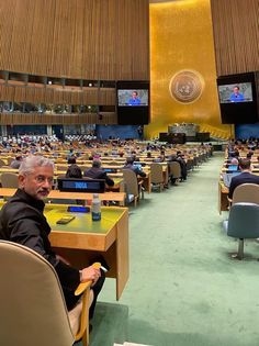 a man sitting at a table in front of a room full of people