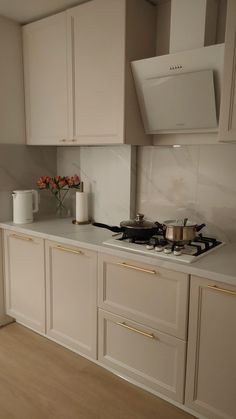 a kitchen with white cabinets and gold trim on the counter tops, along with a stove top oven