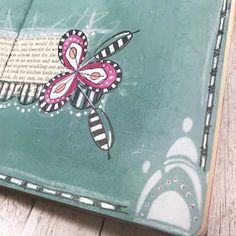 a close up of an open book on a wooden floor with a butterfly painted on the cover