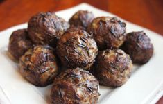 a white plate topped with meatballs on top of a wooden table