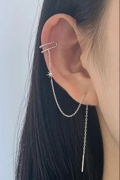 a woman wearing a chain ear cuff with an arrow on the side and a cross in the middle