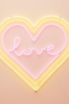 a neon sign that says love in the shape of a heart on a pink wall