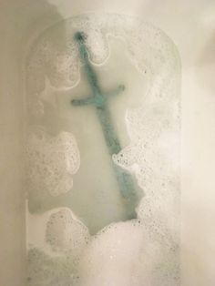 a cross is in the middle of some foamy water with bubbles around it and on top of an ice block