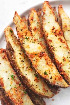 baked potato wedges on a white plate with parmesan cheese and seasoning