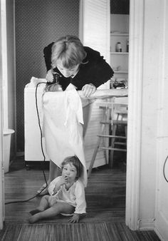 a woman blow drying a child's hair in a room with wood flooring