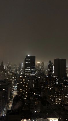 the city skyline is lit up at night, with skyscrapers in the foreground